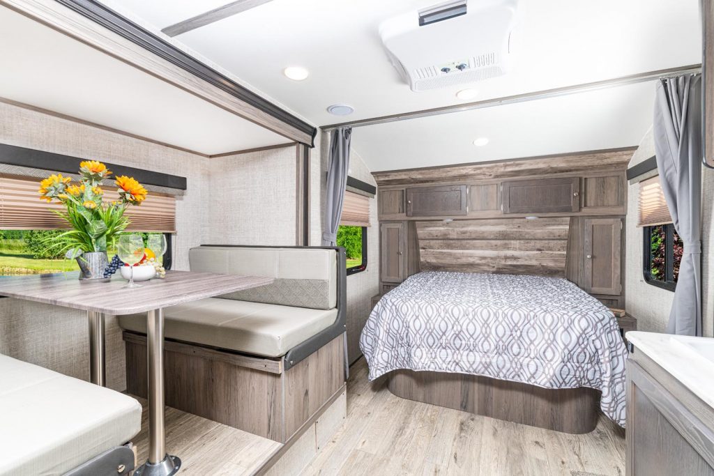 Interior view of the SVT 21QBD, showing Dinette in slide, Queen Bed, Overhead Storage, and Kitchen Counter